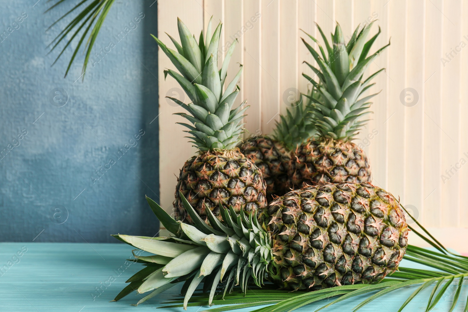 Photo of Fresh pineapples on table against light wall