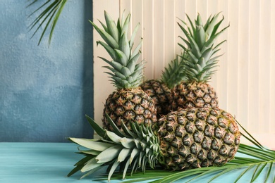 Photo of Fresh pineapples on table against light wall