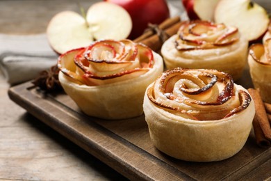 Photo of Freshly baked apple roses on wooden table, closeup. Beautiful dessert