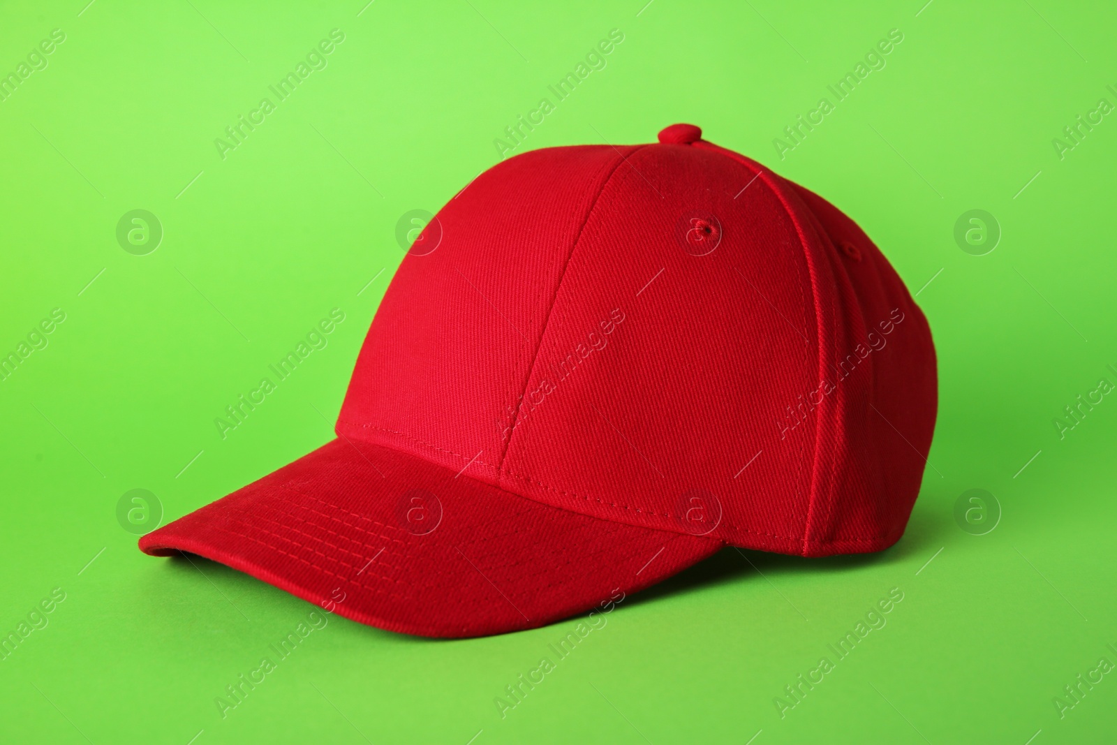 Photo of Stylish red baseball cap on light green background