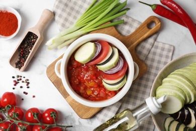 Photo of Dressing for delicious ratatouille and different vegetables on white marble table, flat lay