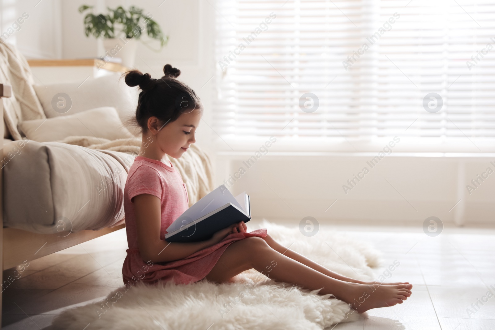 Photo of Little girl reading fairy tale in living room