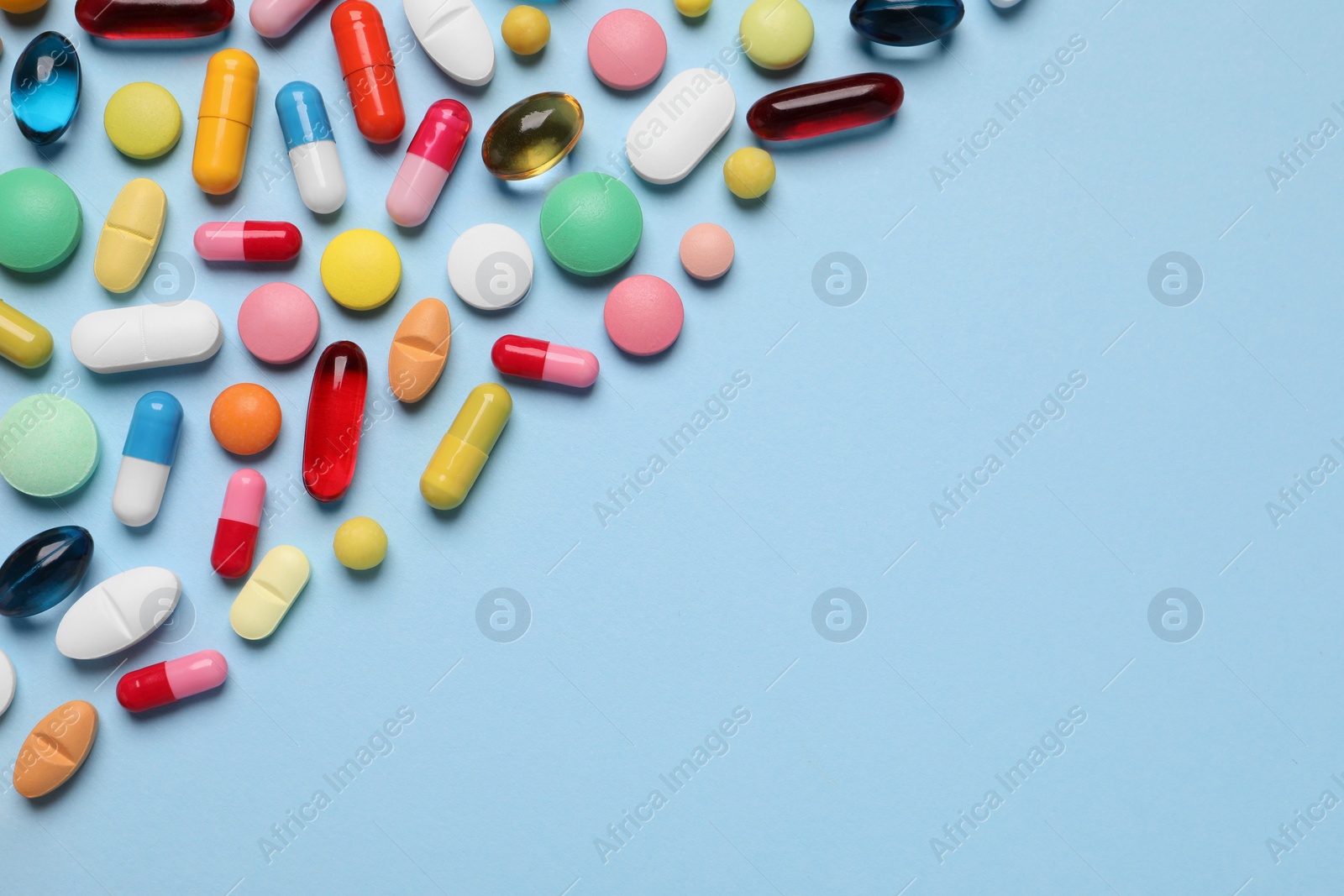 Photo of Many different pills on light blue background, flat lay. Space for text