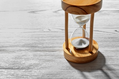 Photo of Hourglass with flowing sand on light wooden background. Time management