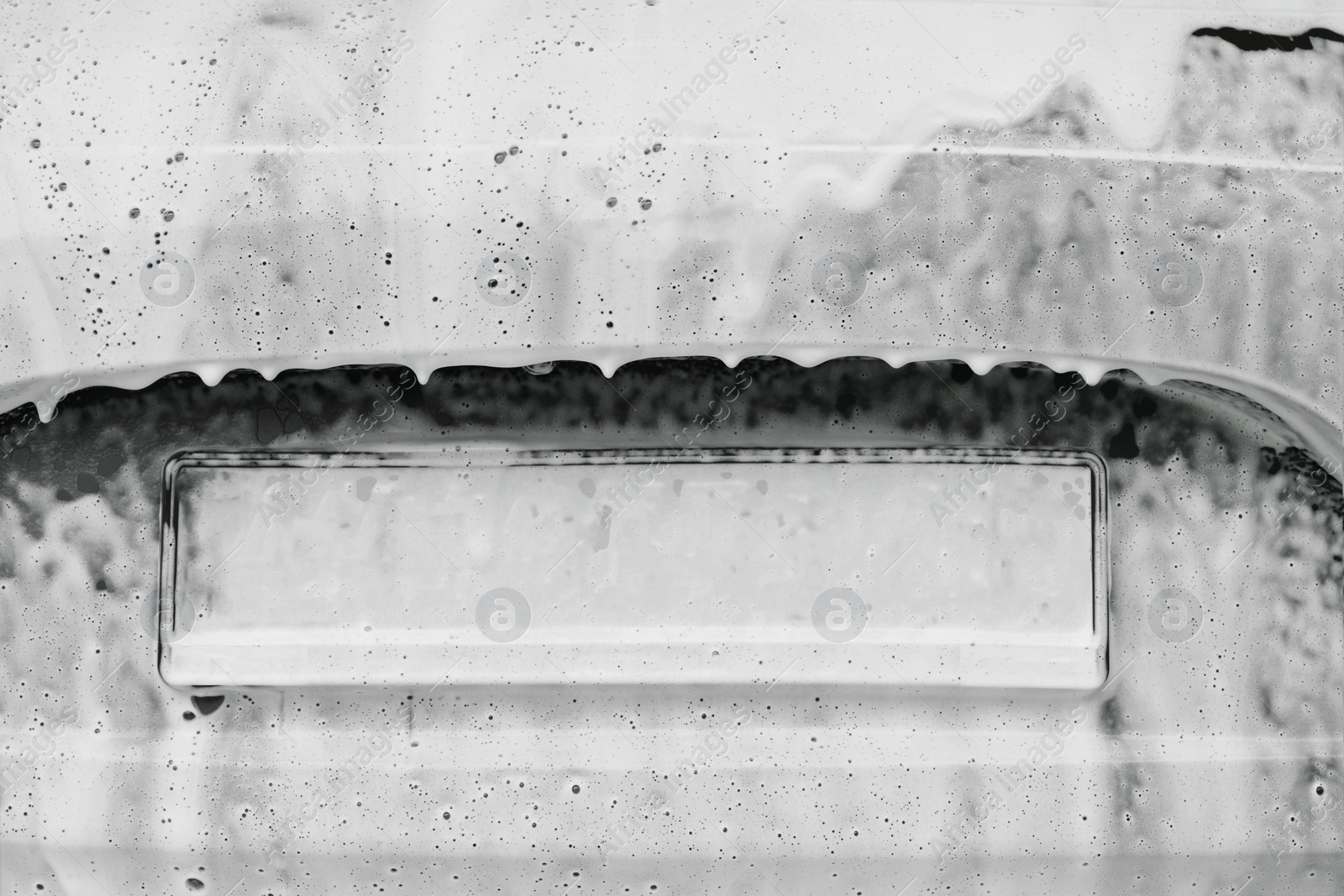 Photo of Auto trunk with cleaning foam at car wash, closeup