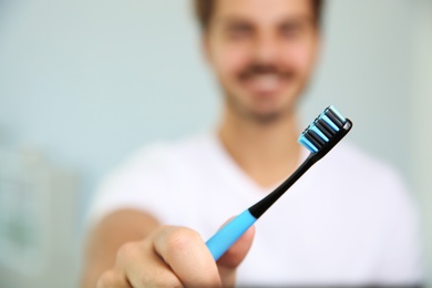 Photo of Man with toothbrush on blurred background, focus on hand