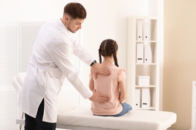 Chiropractor examining child with back pain in clinic