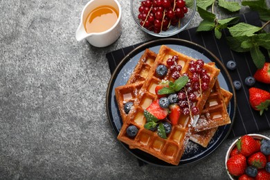 Delicious Belgian waffles with berries served on grey table, flat lay. Space for text