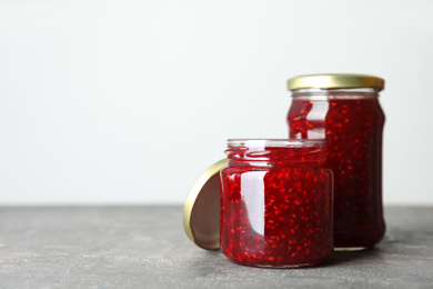 Jars of raspberry jam on grey table. Space for text