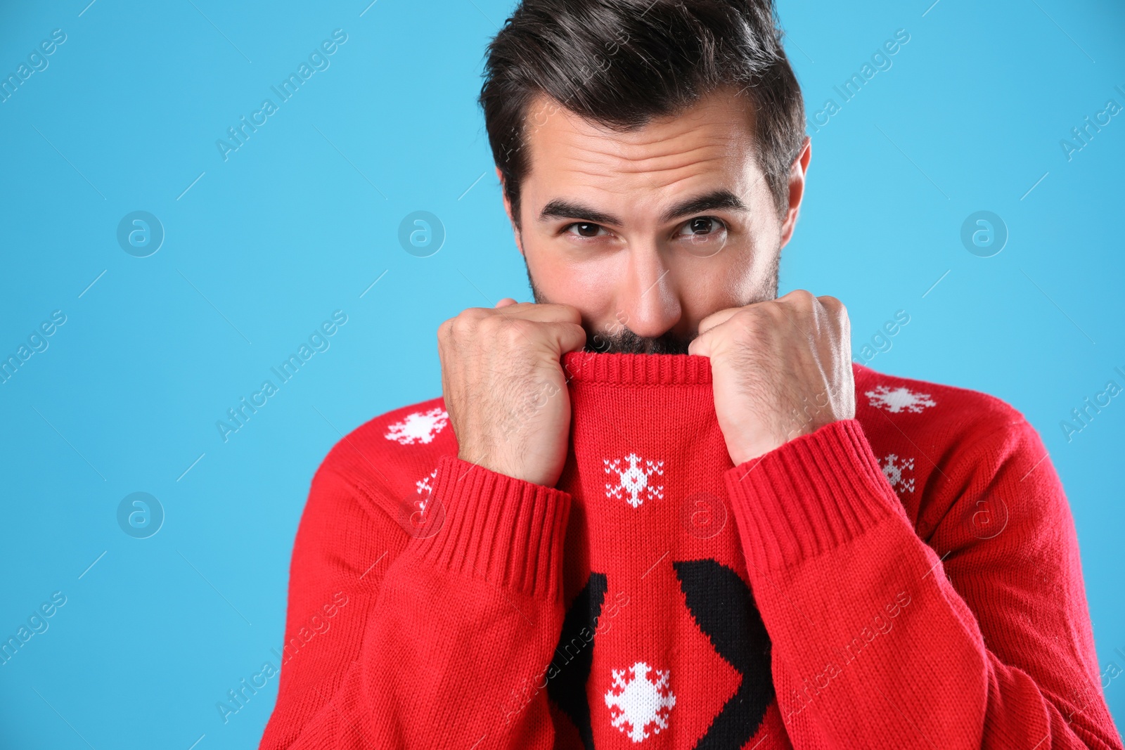 Photo of Young man in Christmas sweater on light blue background