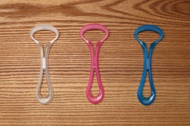 Photo of Different tongue cleaners on wooden table, flat lay