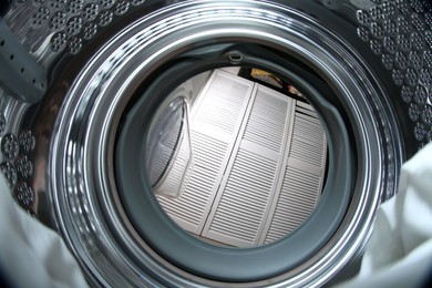 Photo of Clothes in washing machine indoors, view from inside. Laundry day