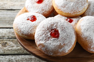 Delicious donuts with jelly and powdered sugar on wooden pastry stand, closeup
