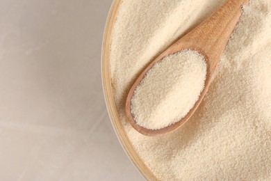 Photo of Bowl with semolina and spoon on light table, top view. Space for text