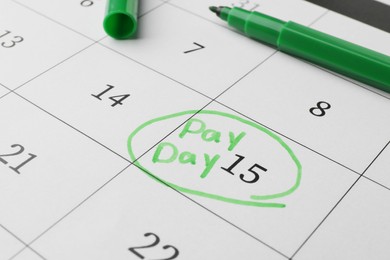 Photo of Green felt pen on calendar page with marked payday date, closeup