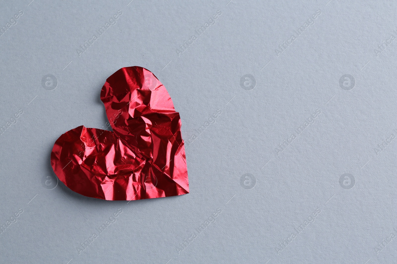 Photo of Red crumpled paper heart on gray background, top view with space for text. Breakup concept