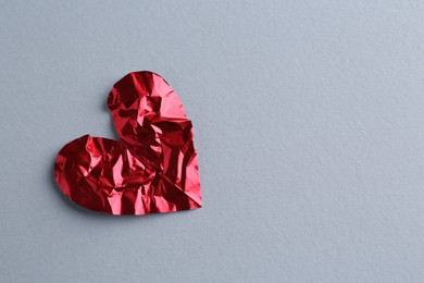 Photo of Red crumpled paper heart on gray background, top view with space for text. Breakup concept