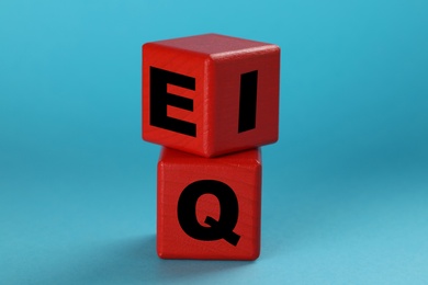 Photo of Red cubes with letters E, I and Q on light blue background