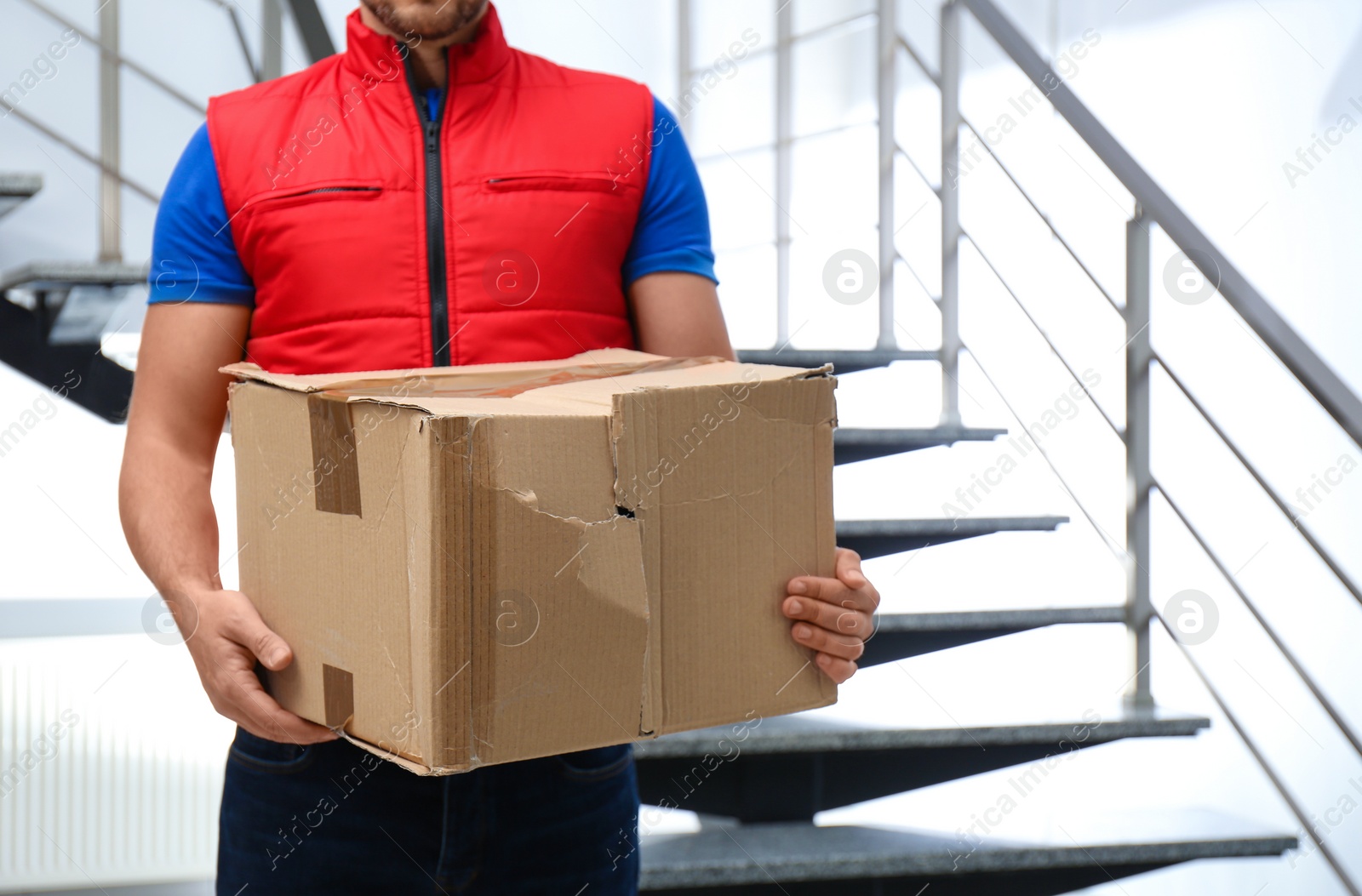 Photo of Courier with damaged cardboard box indoors, closeup. Poor quality delivery service