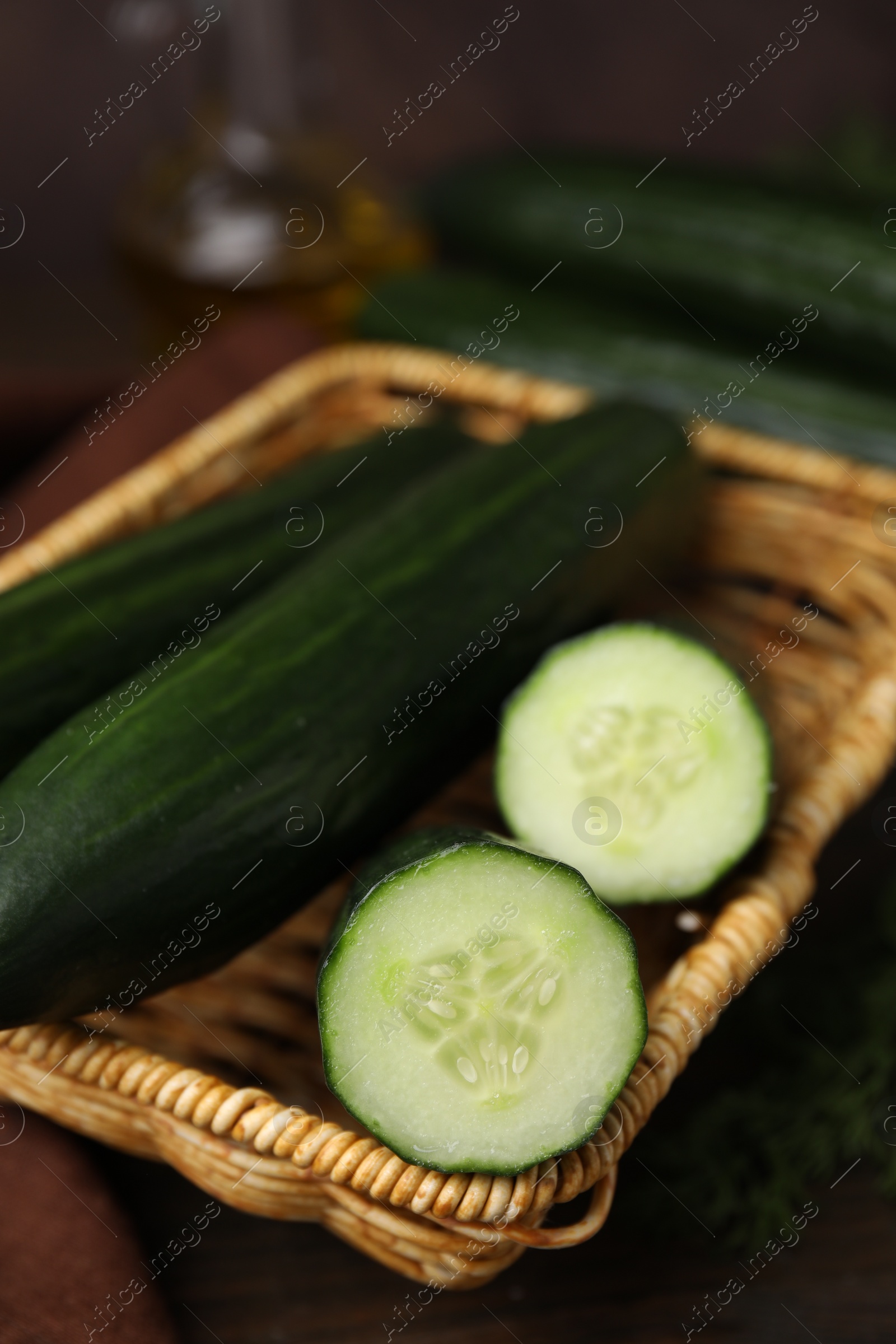 Photo of Fresh cucumbers in wicker basket on table, closeup