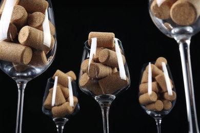 Glasses full of many wine corks on black background, low angle view