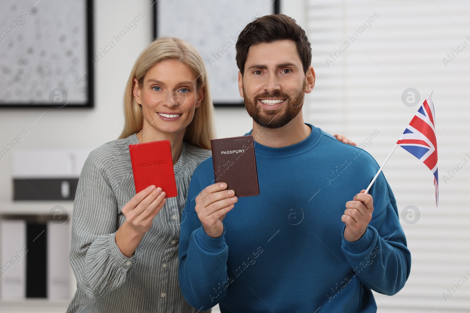 Photo of Immigration. Happy couple with passports and flag of United Kingdom indoors