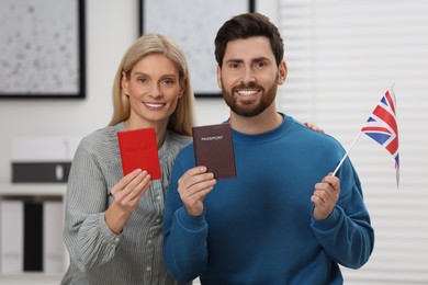 Immigration. Happy couple with passports and flag of United Kingdom indoors