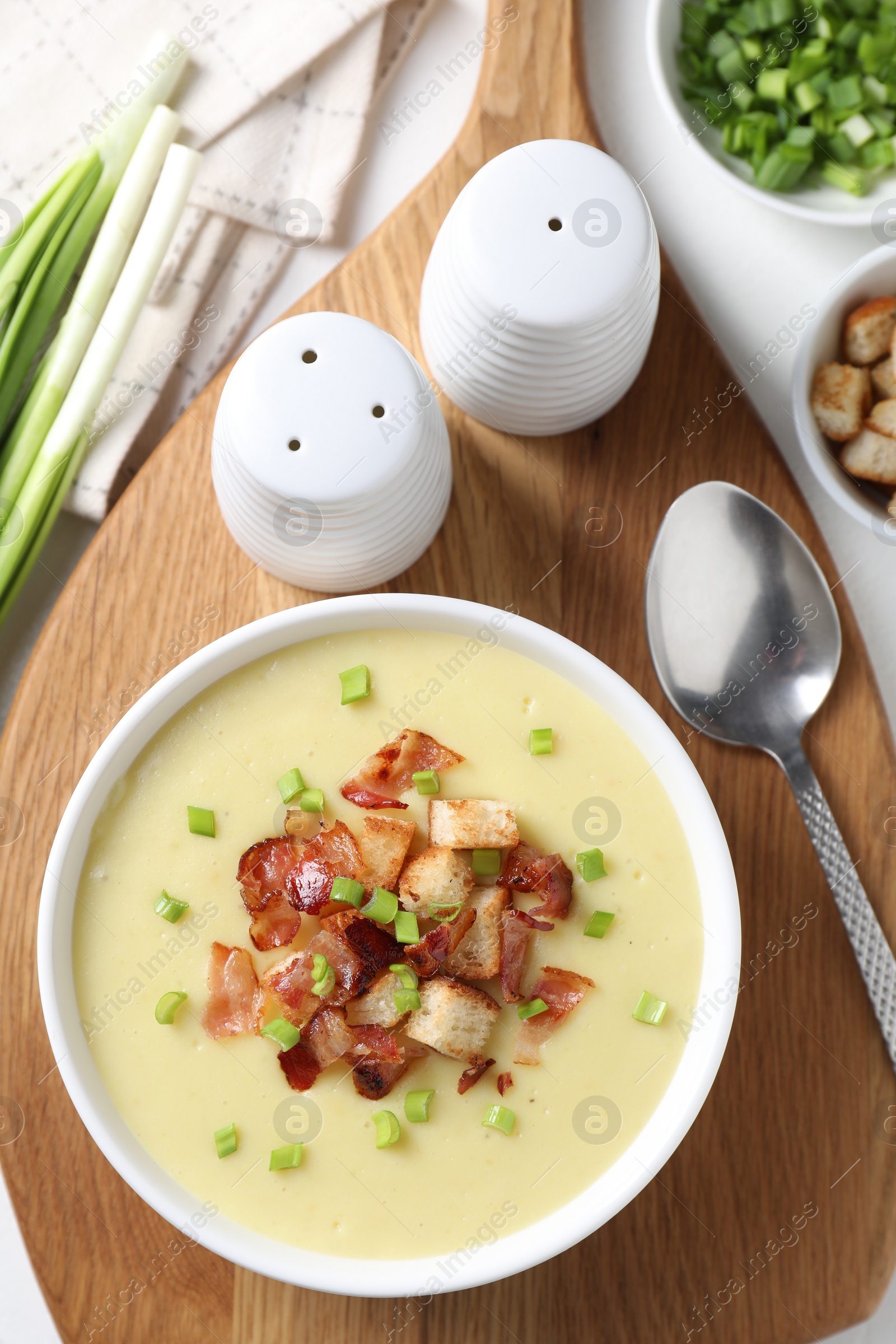 Photo of Tasty potato soup with bacon in bowl served on white table, flat lay