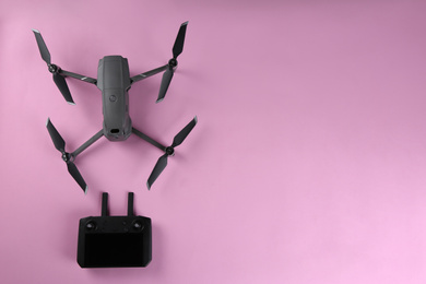 Photo of Modern drone with controller on pink background, flat lay. Space for text