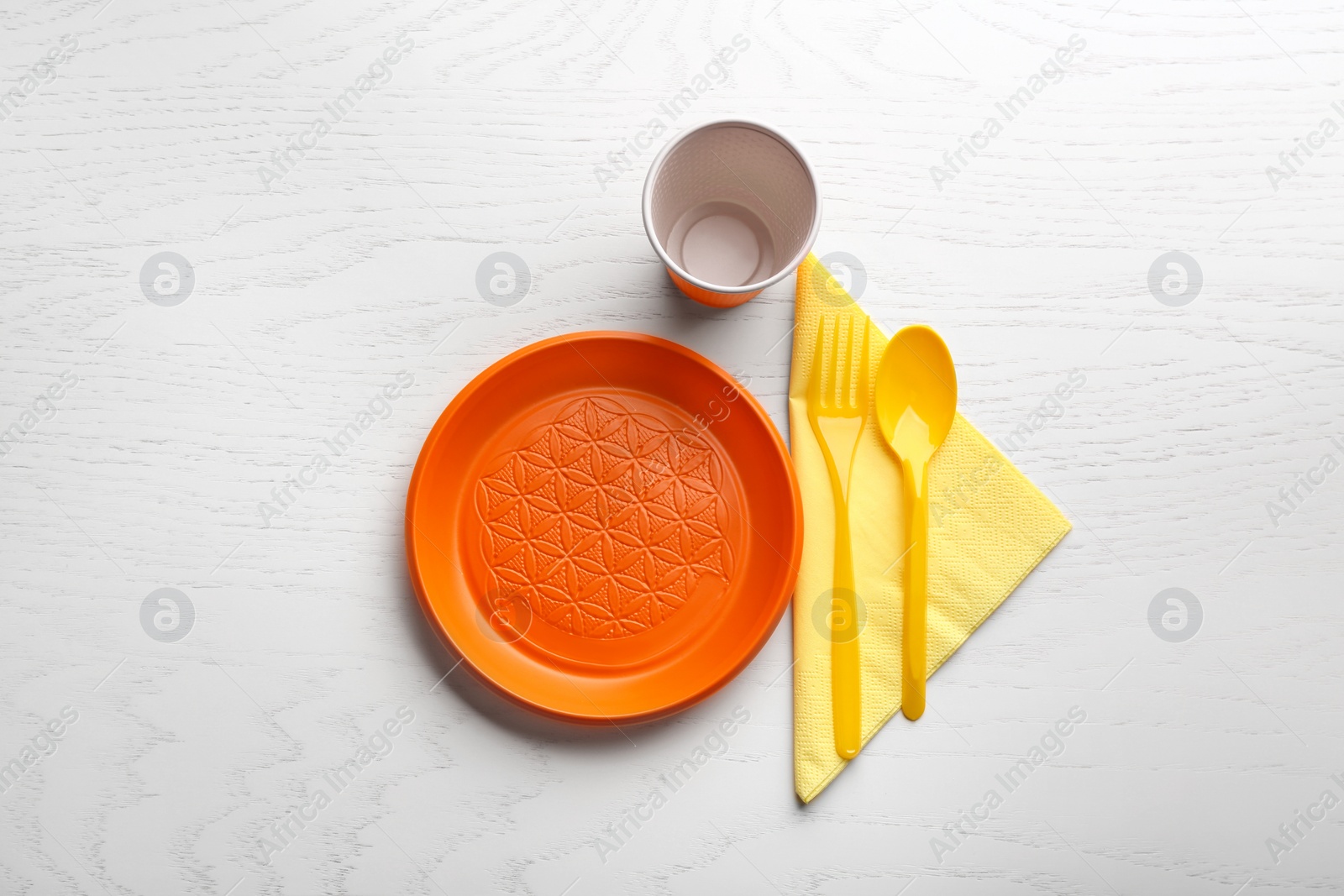 Photo of Composition with plastic dishware on wooden table, flat lay. Picnic table setting