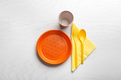 Composition with plastic dishware on wooden table, flat lay. Picnic table setting