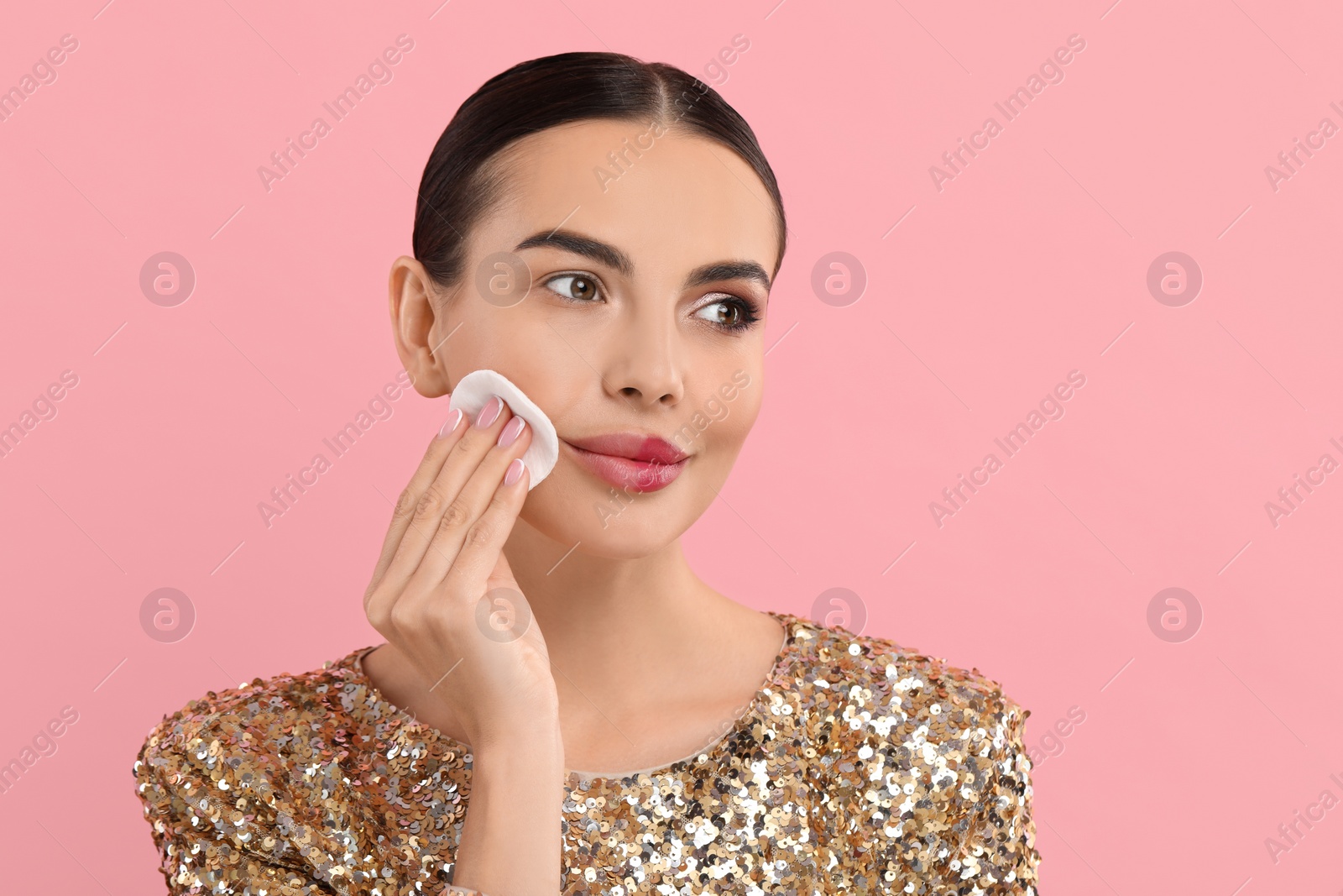 Photo of Beautiful woman removing makeup with cotton pad on pink background. Space for text