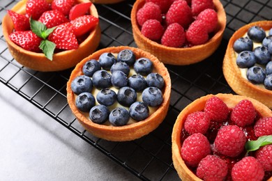 Tartlets with different fresh berries on grey table. Delicious dessert