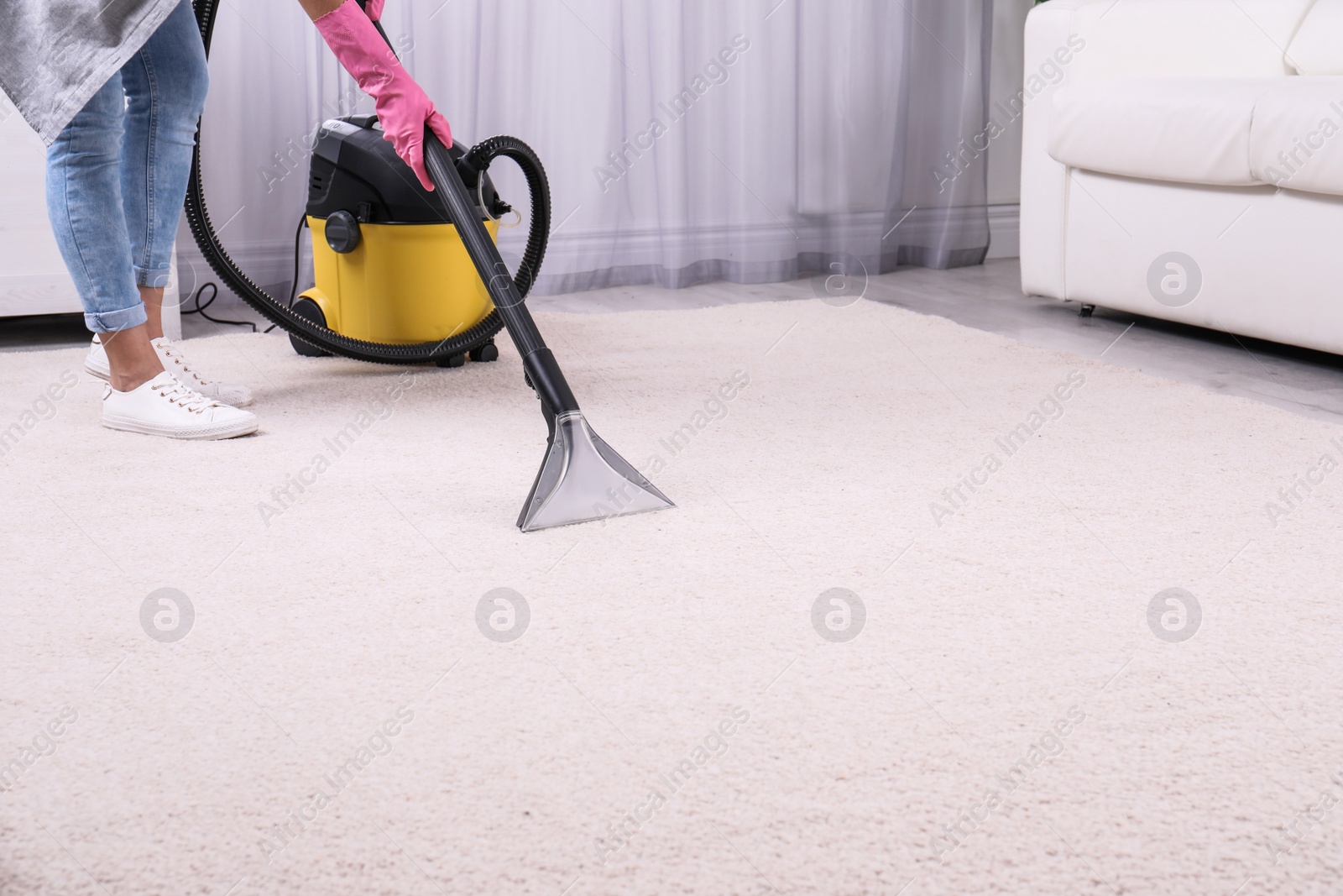 Photo of Woman cleaning carpet with vacuum cleaner, closeup. Space for text