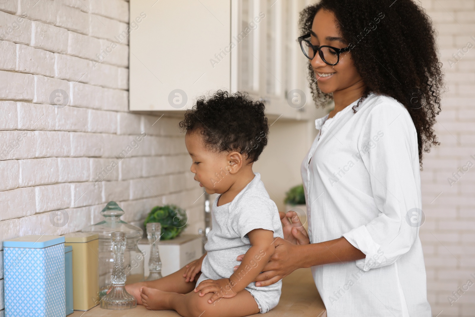 Photo of African-American woman with her baby in kitchen. Happiness of motherhood