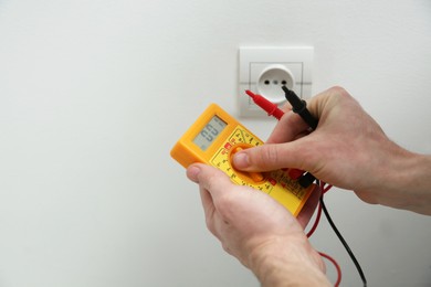 Photo of Electrician with tester checking voltage, closeup view