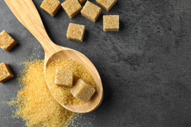 Photo of Spoon with brown sugar cubes on grey table, flat lay. Space for text