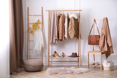 Photo of Rack with stylish warm clothes, shoes and accessories in modern dressing room