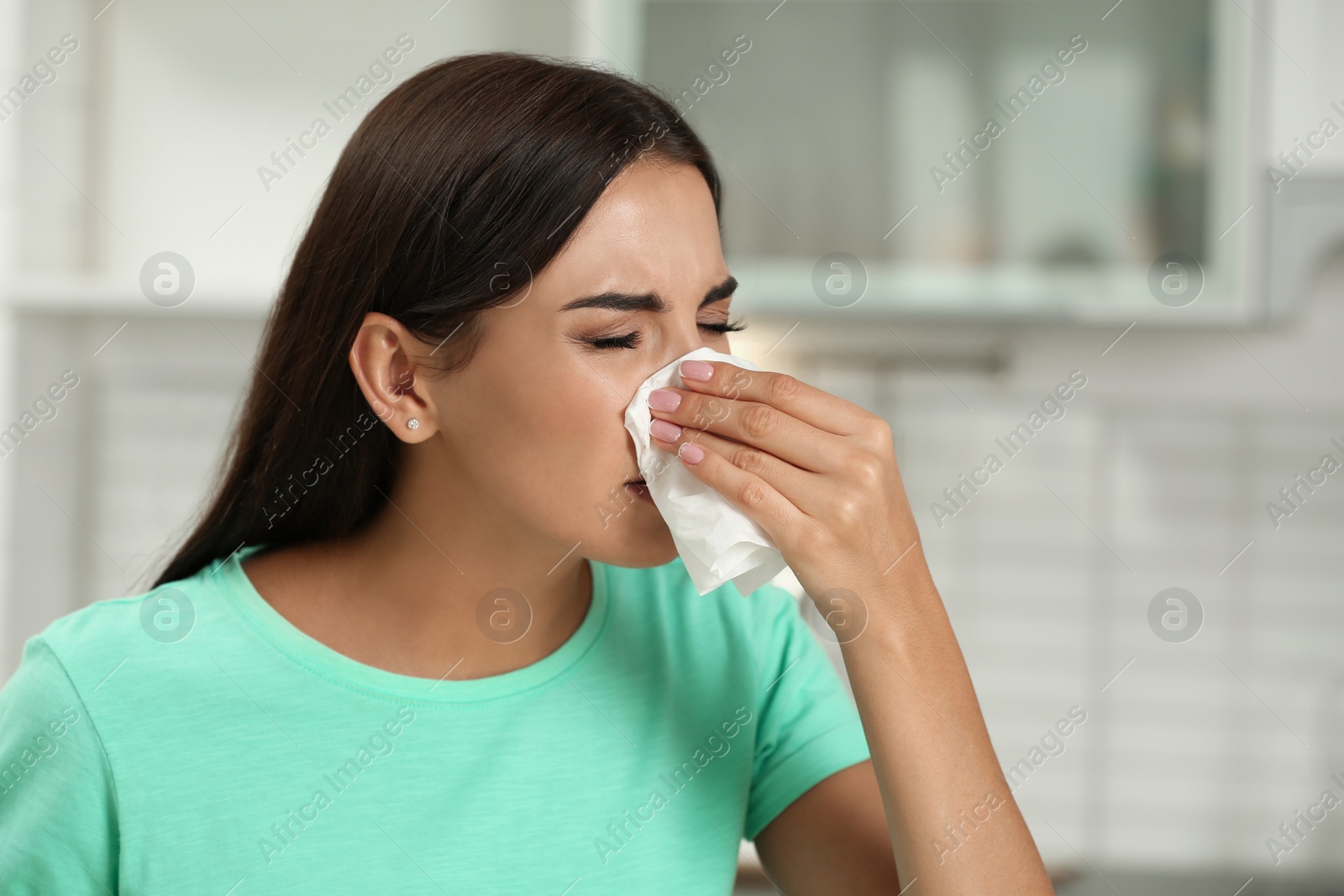 Photo of Young woman suffering from allergy in kitchen