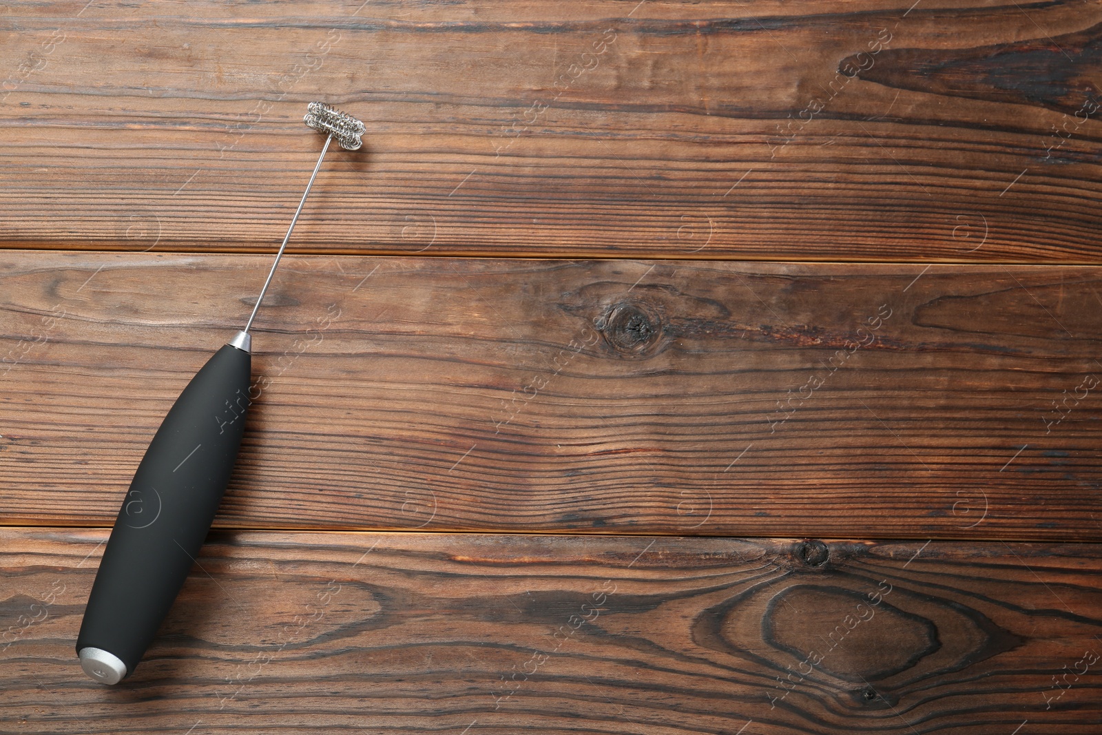 Photo of Black milk frother wand on wooden table, top view. Space for text