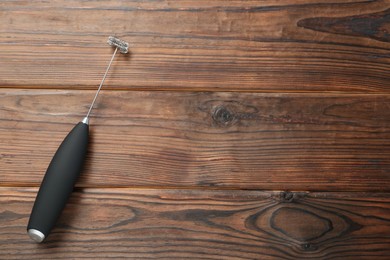 Photo of Black milk frother wand on wooden table, top view. Space for text