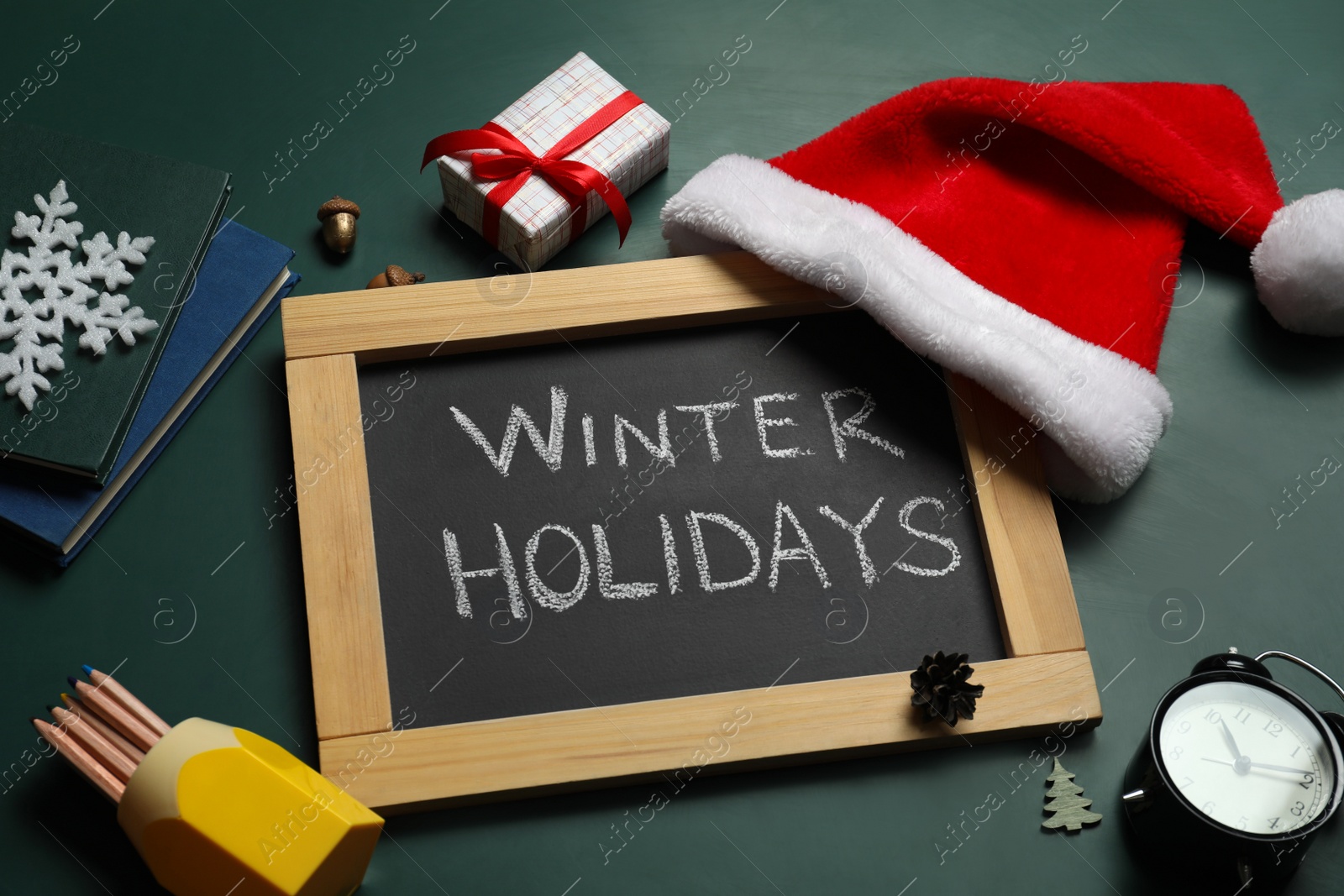 Photo of Blackboard with text Winter Holidays and Christmas decor on green background, above view