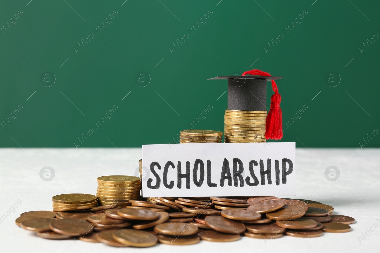 Photo of Paper with word Scholarship, graduation cap and coins on white table