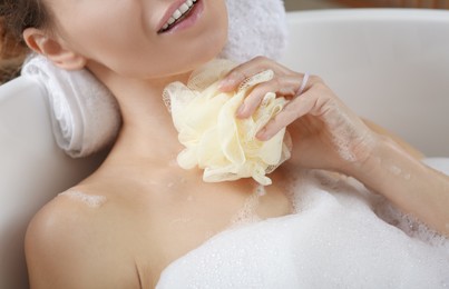 Photo of Woman rubbing her neck with sponge while taking bath, closeup