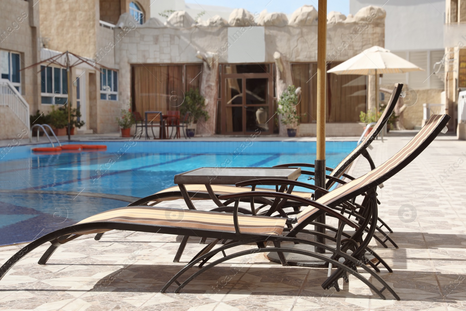 Photo of Comfortable sunbeds near swimming pool at luxury hotel