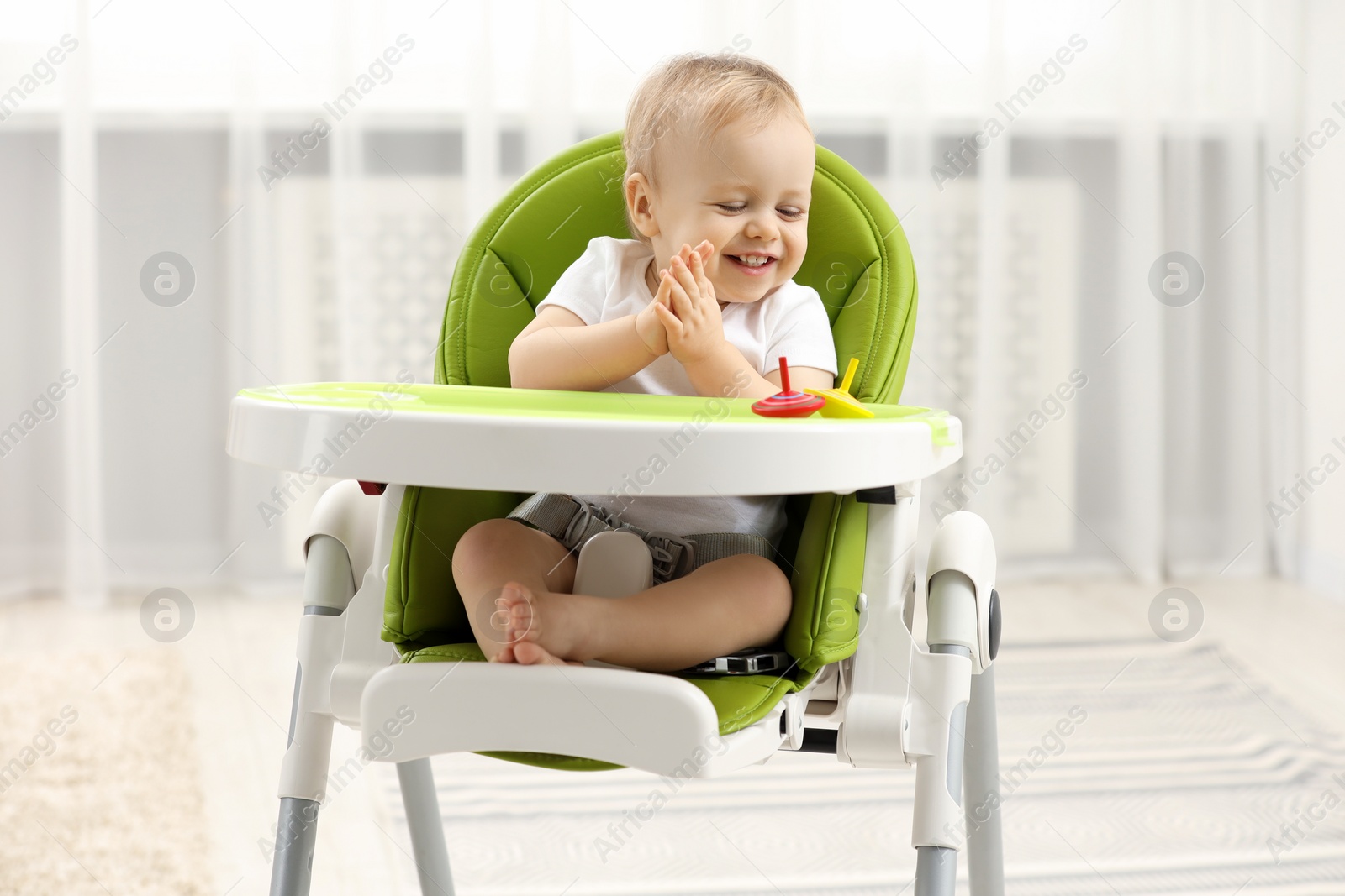 Photo of Children toys. Cute little boy playing with spinning tops in high chair at home