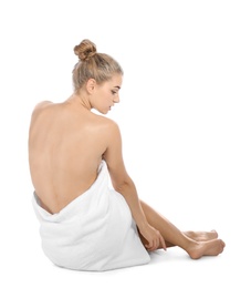 Young woman with soft towel sitting on white background