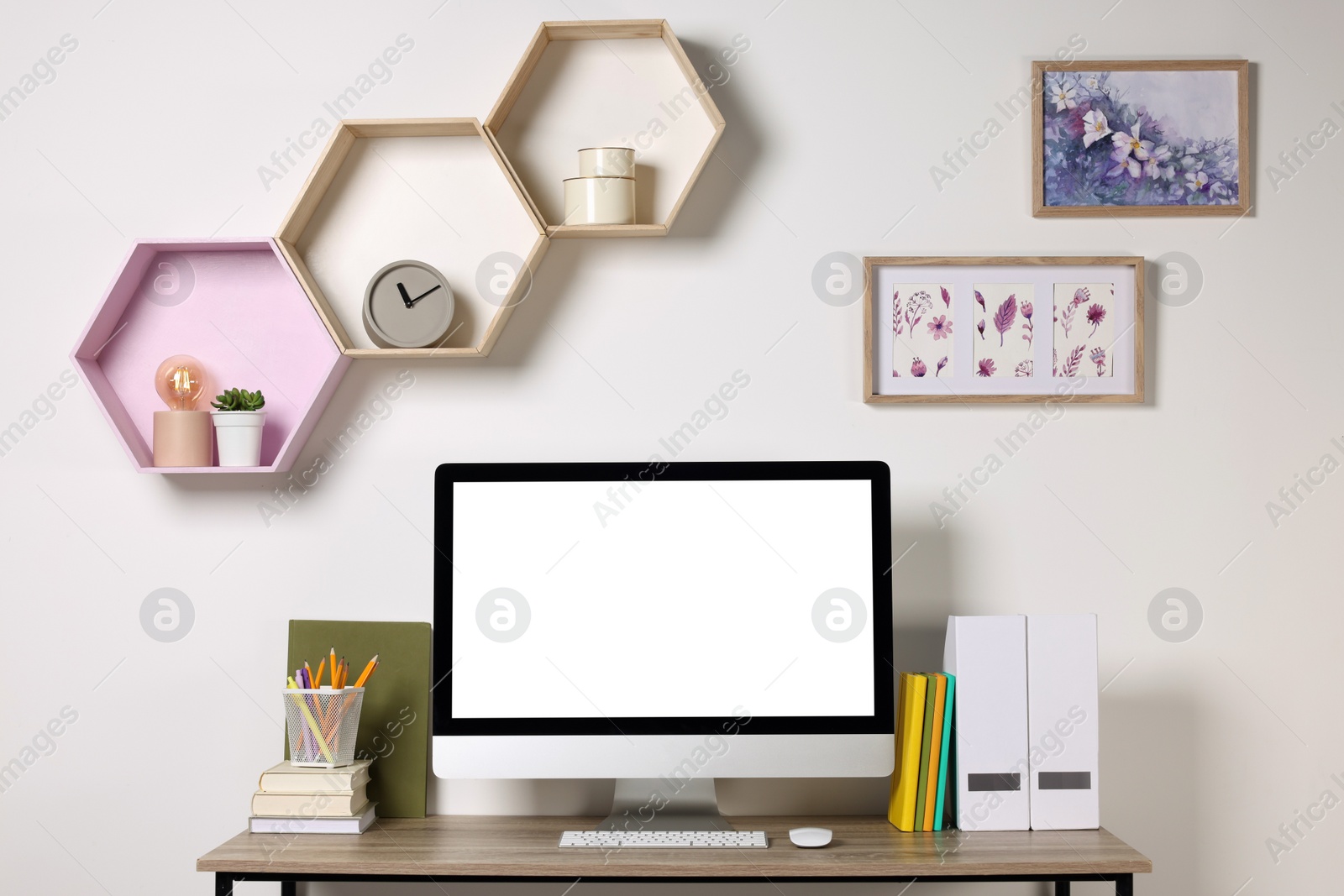 Photo of Computer on wooden desk and shelves indoors. Cozy workspace