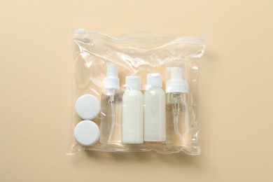 Cosmetic travel kit in plastic bag on beige background, top view. Bath accessories