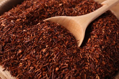 Photo of Spoon dry rooibos leaves in wooden bowl, closeup